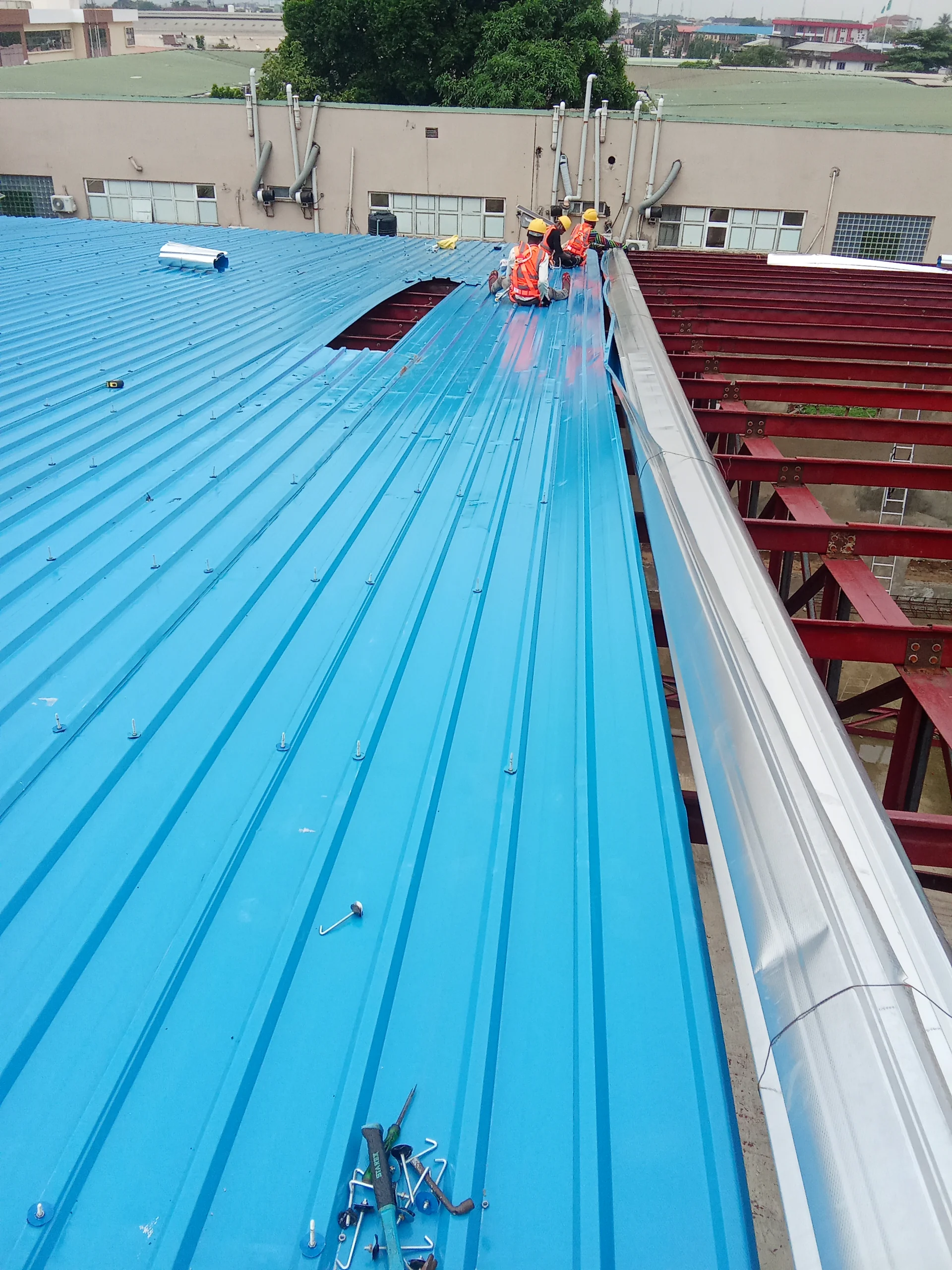 Professional workers installing modern aluminum roofing on a construction site in Nigeria